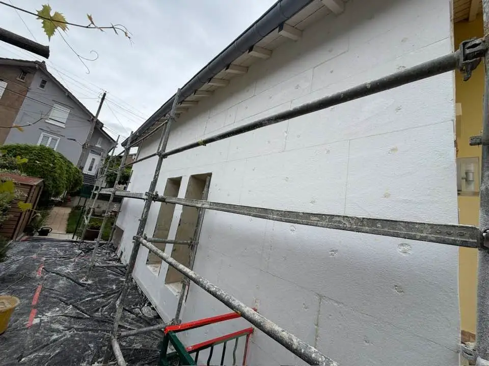 Pignon de maison recouvert de panneaux isolants blancs, échafaudage en place