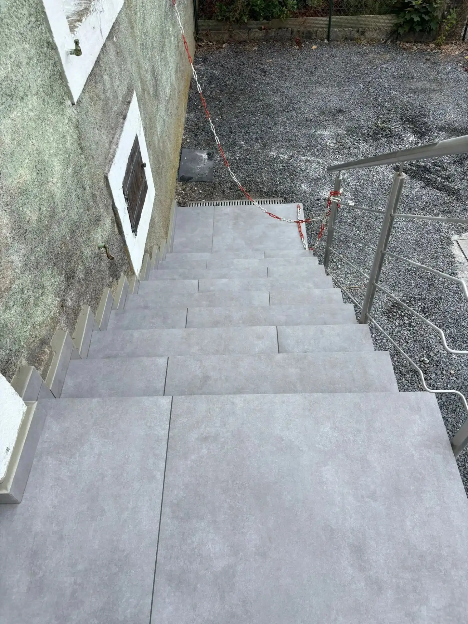 Escalier extérieur habillé de dalles en grès cérame gris, avec main courante