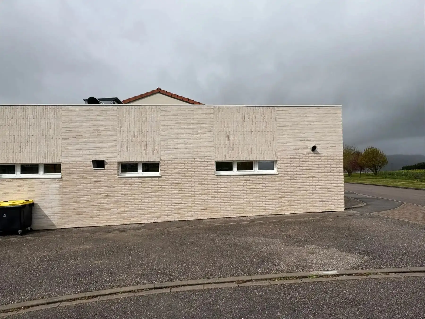 Façade d’un bâtiment habillée d’un parement clair, vue depuis la rue