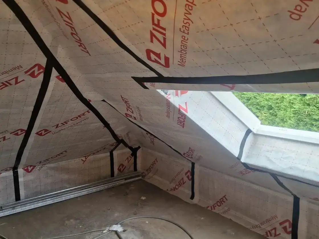 Isolation de combles avec membrane pare-vapeur posée autour d’une fenêtre de toit