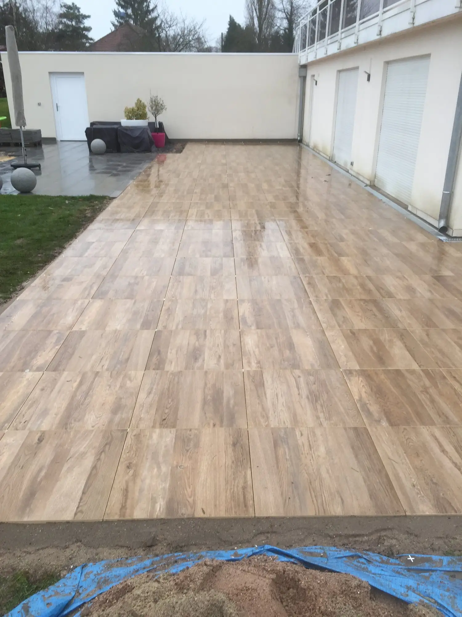 Terrasse en grandes dalles effet bois posées le long d’une maison
