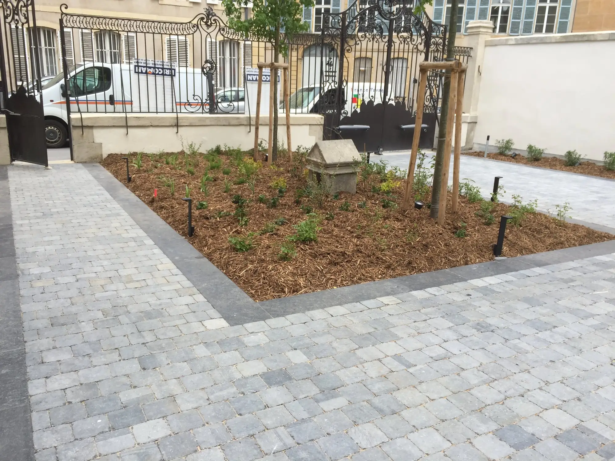 Pavage en pavés gris avec bordures et massifs devant une maison de ville