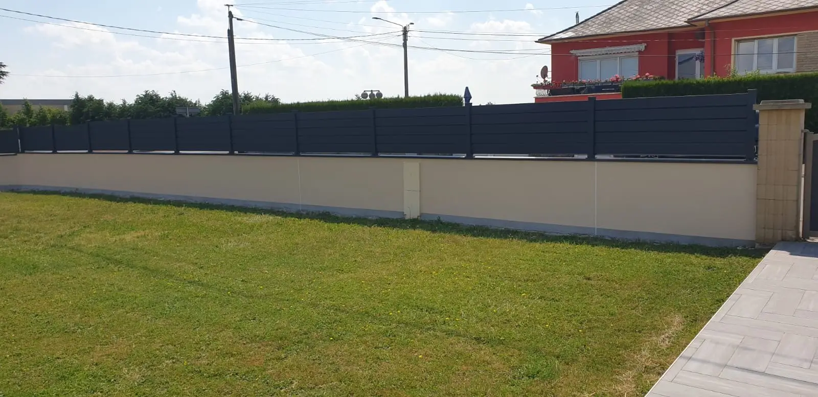 Clôture en panneaux aluminium anthracite posée sur un muret enduit